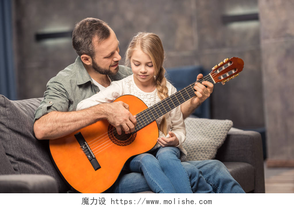 微笑的父亲和教女儿弹吉他父亲和女儿玩吉他